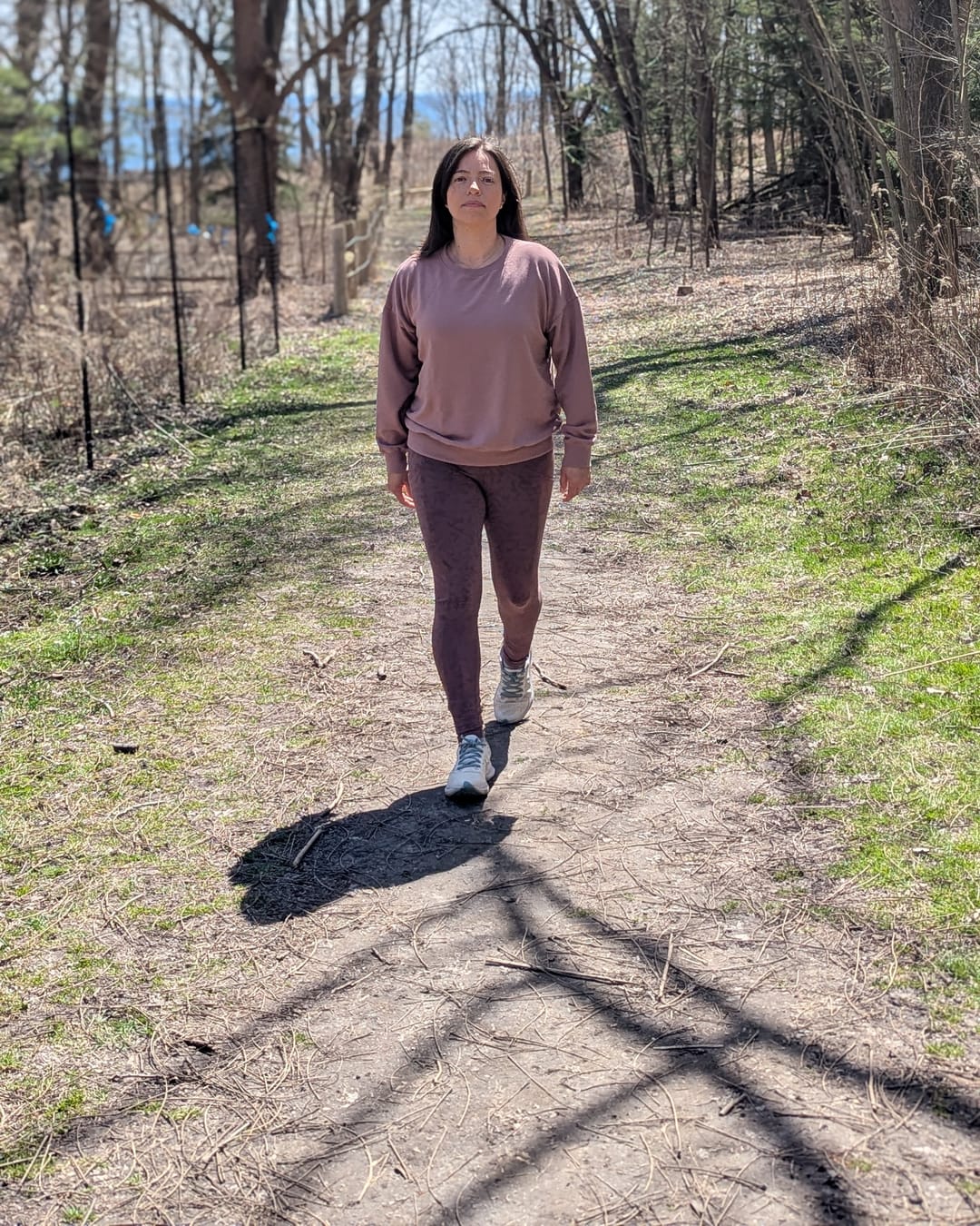 Victoria Chavarro walking a wooded trail beside the lake